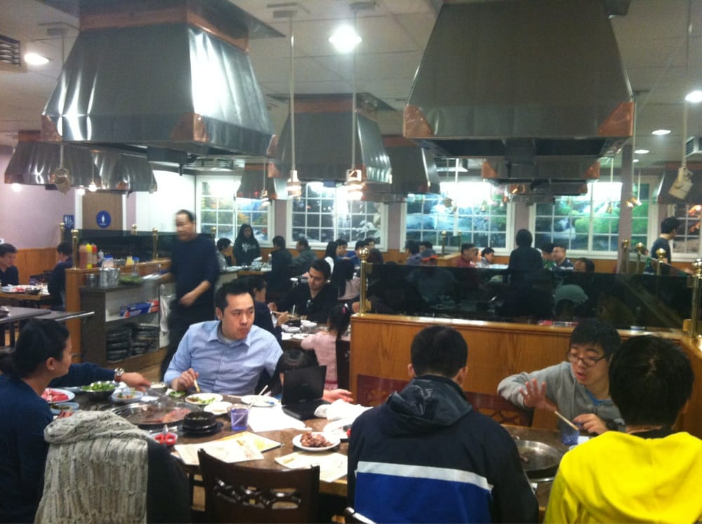 Busy dining room with a grill and an overhead vent at every table